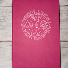 Load image into Gallery viewer, Pink notebook with white emblem on a wooden surface