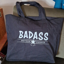 Load image into Gallery viewer, black tote bag with 'BADASS' text on a couch
